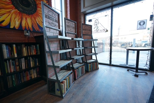 Steel and wood leaning ladder shelves filled with books inside a coffee shop