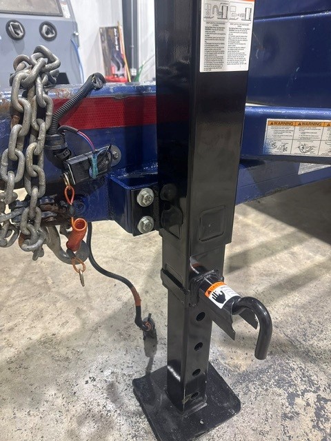 Black drop-leg trailer jack and safety chains mounted on a blue trailer tongue