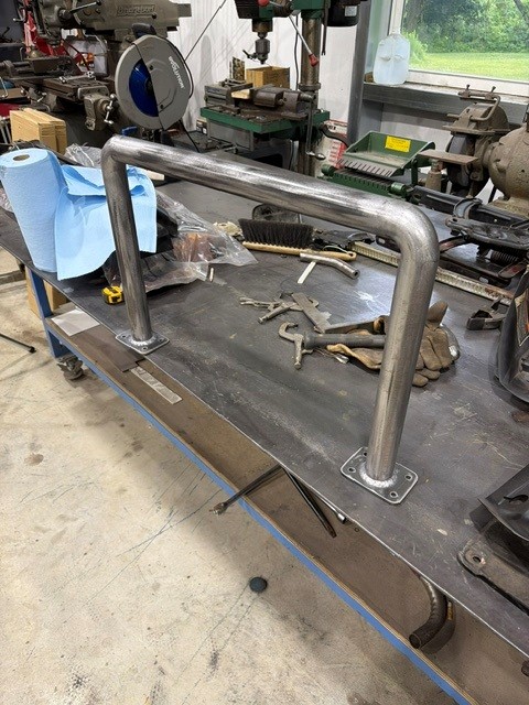 Polished stainless tube grab rail with flanged base plates on a shop layout table