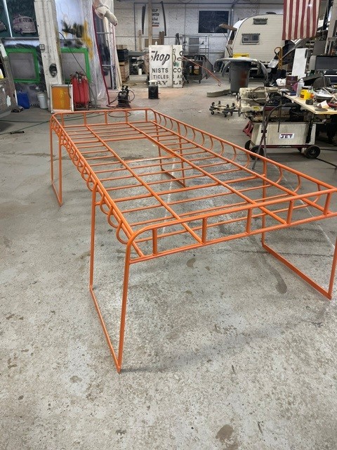 Large orange powder-coated tubular steel roof rack standing in the shop