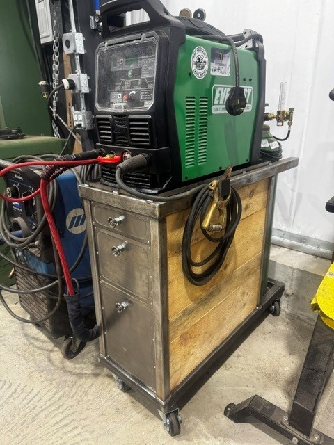 Custom steel and wood welding cart on casters holding a MIG welder and gas bottle