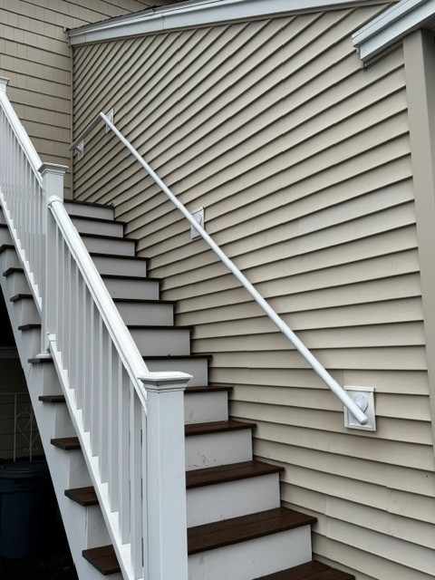 White powder-coated wall-mounted hand rail running down exterior stairs